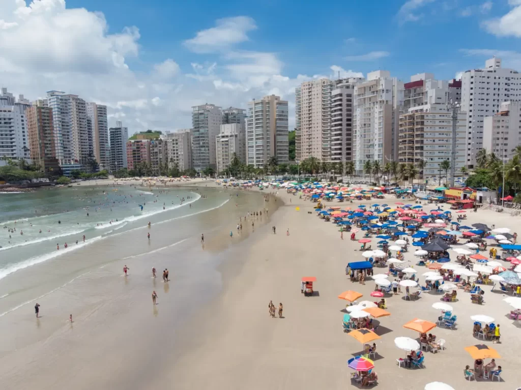 Praia no Guarujá em São Paulo com mar azul e faixa de areia extensa, uma dica de turismo no litoral Paulista