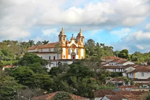 Vista panorâmica da cidade de Tiradentes com torres de igrejas surgindo entre o casario e a serra