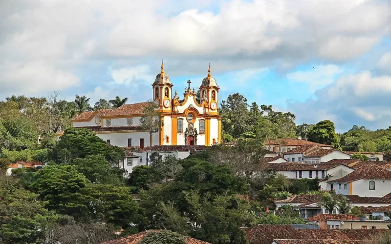 Vista panorâmica da cidade de Tiradentes com torres de igrejas surgindo entre o casario e a serra